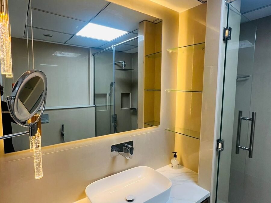 Walnut vanity with marble top, backlit mirror and walk-in shower