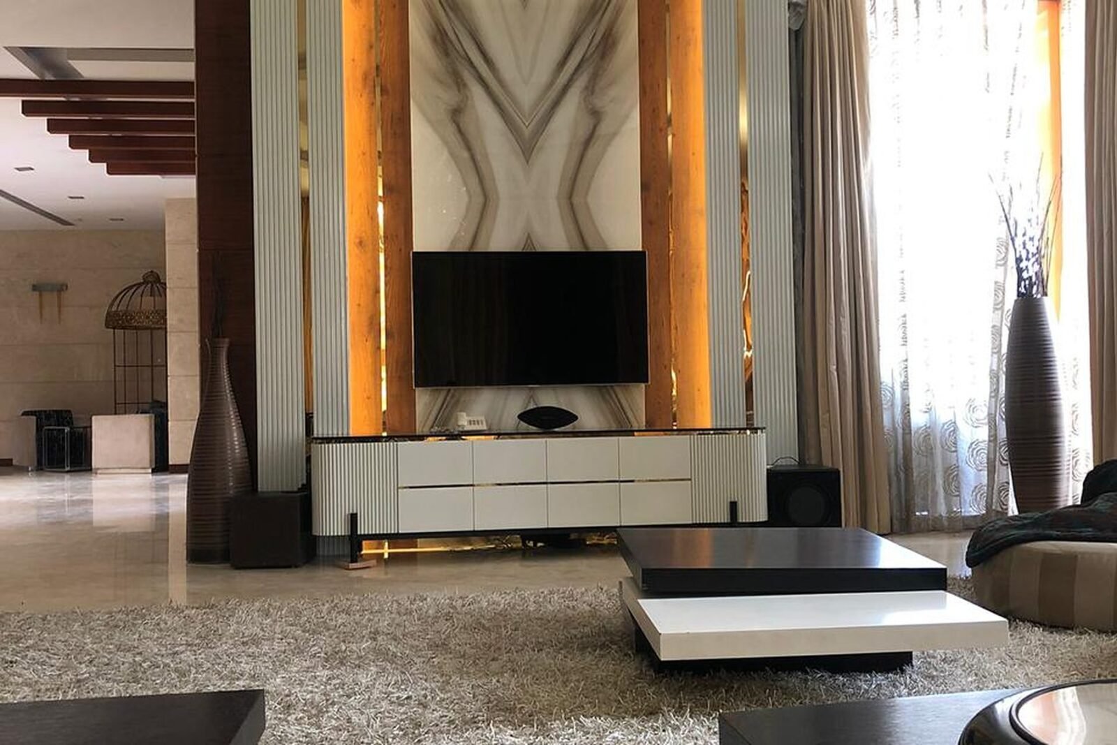 Fluted panelling and backlit marble TV feature wall in a villa living room