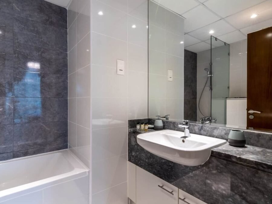 Grey marble bathroom with white gloss vanity, mirrored wall and bath