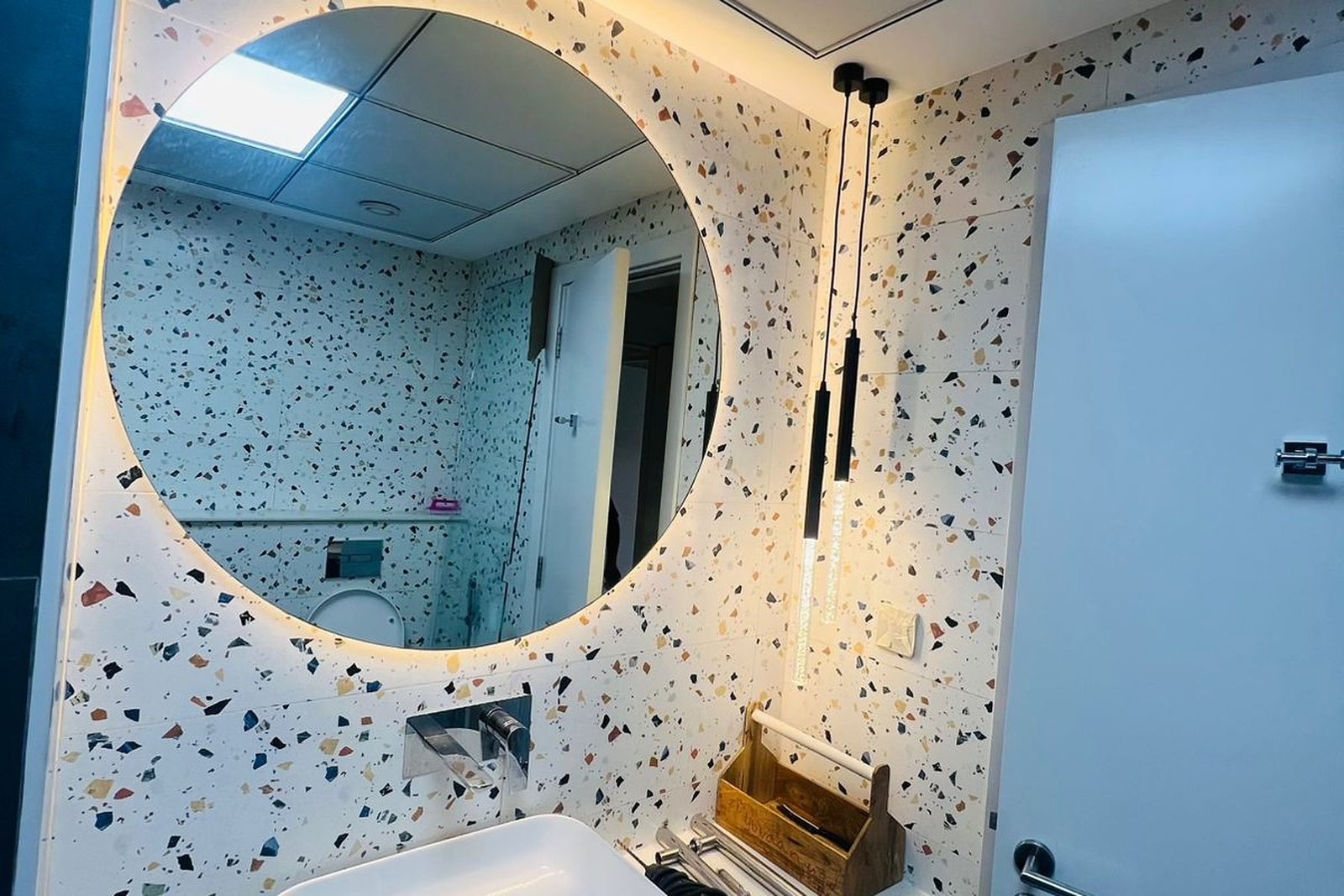 Terrazzo guest bathroom with a round backlit mirror