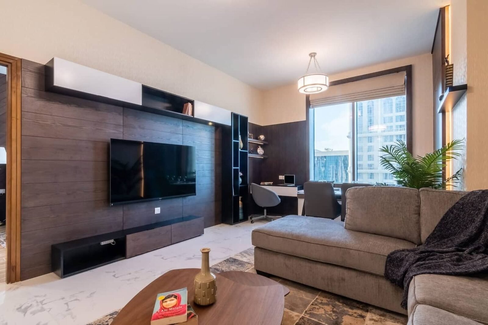 Dark wood media wall with integrated TV, shelving and desk in a Business Bay apartment