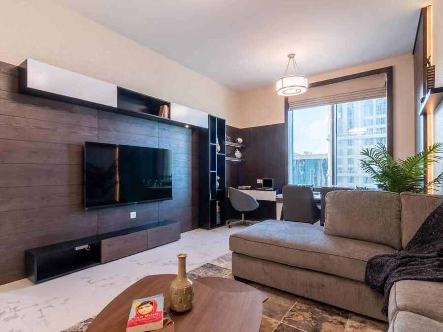 Dark wood media wall with integrated TV, shelving and desk in a Business Bay apartment