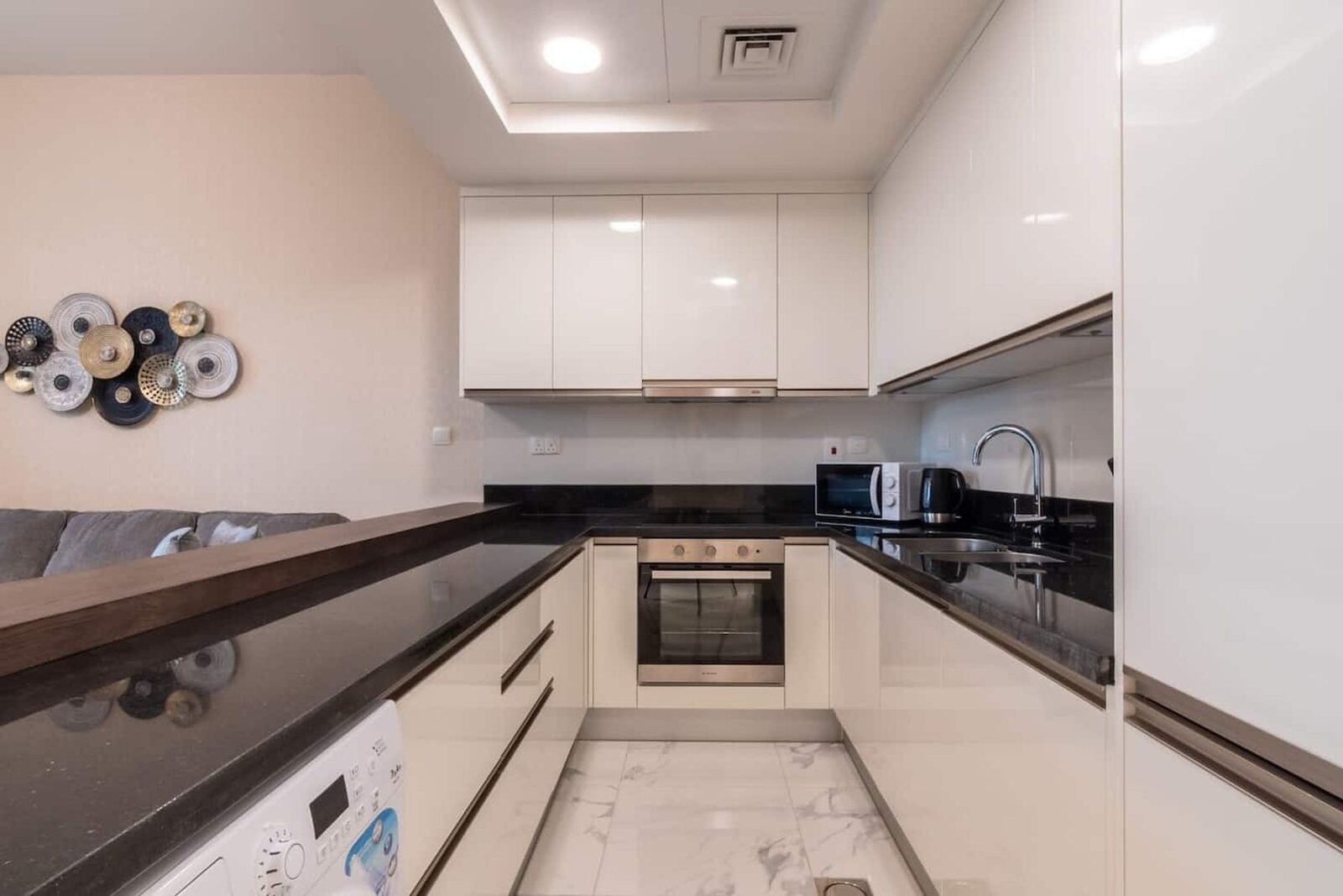 White gloss galley kitchen with black granite worktop and timber breakfast bar