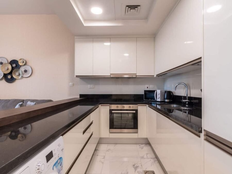 White gloss galley kitchen with black granite worktop and timber breakfast bar