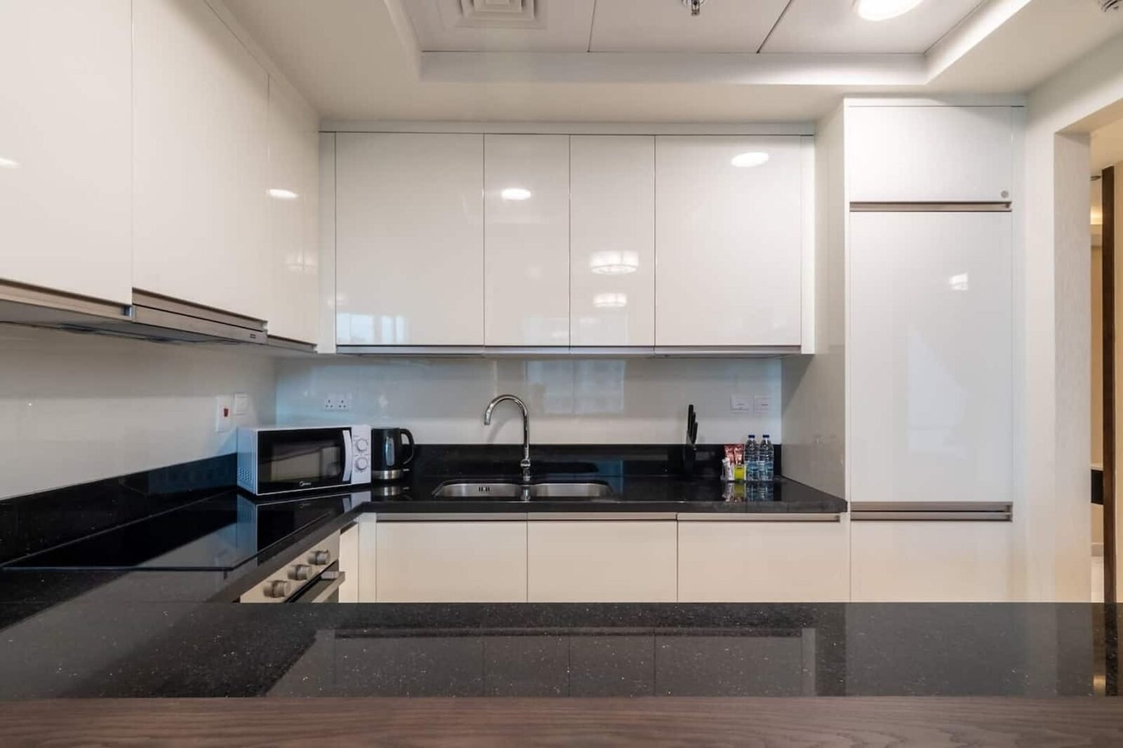 White gloss U-shaped kitchen with black granite worktop and timber breakfast bar