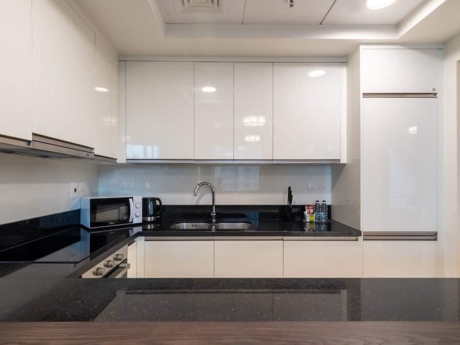 White gloss U-shaped kitchen with black granite worktop and timber breakfast bar